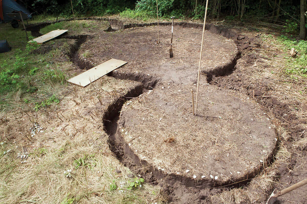 Roekel and Isabel dug a trench to remove the topsoil and get to the sandy layer beneath, which is compacted and much steadier as a foundation. Then, they filled the trench with gravel.