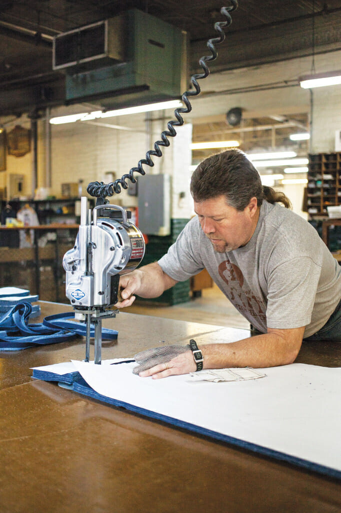 Employee Will Holt cuts fabric from a paper pattern