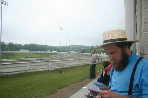 Brenneman consults the program as horses warm up for one of the day's qualifying races at The Meadows racetrack in Washington, Pa.