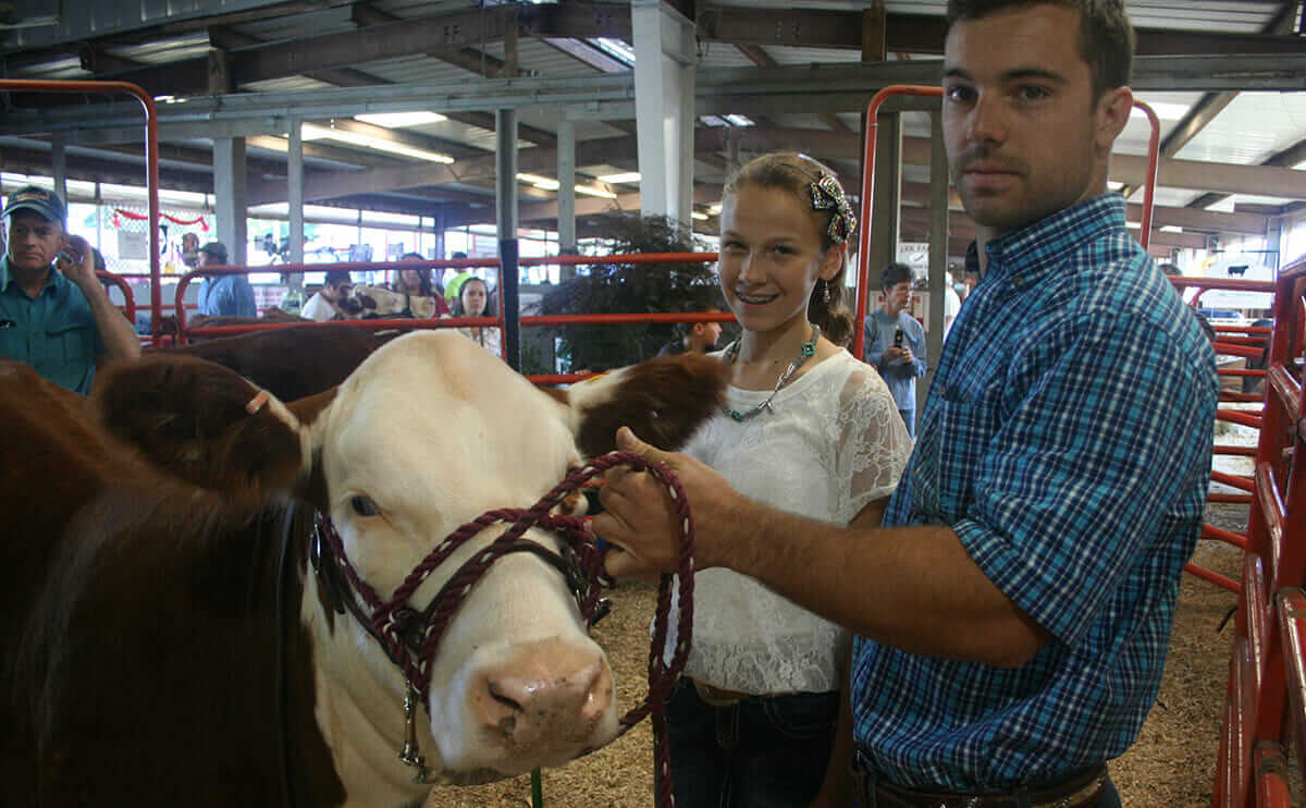 Daniel Fleishman (right) helps his cousin, Abigail Allen, 13, get ready to enter the show ring. At 22, Fleishman is too old to compete at the junior level himself, and is handing off the reins to younger members of the family.