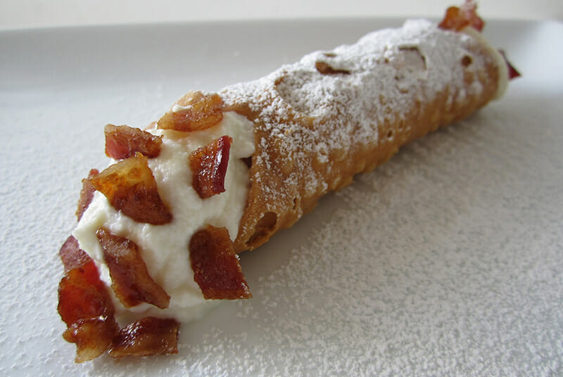 The ultimate sweet-savory combo: chewy, caramelized bacon pieces paired with Ole's sweet, smooth ricotta cheese filling in a fried, crunchy pastry shell from<br />
Ole's Cannoli.