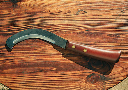 A curved scythe with a Japanese wood handle. Each tool has a very particular use in Japanese farming.