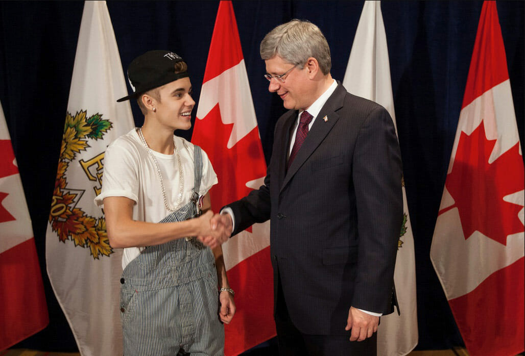 Justin Bieber with the Prime Minister of Canada in a pair of bib overalls (with one strap undone).