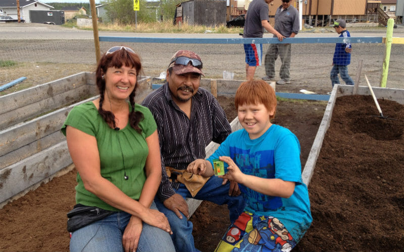 Lone Sorensen with Fred Sangris, a former Chief who is learning to grow vegetables for his caribou stew, and David, a student.
