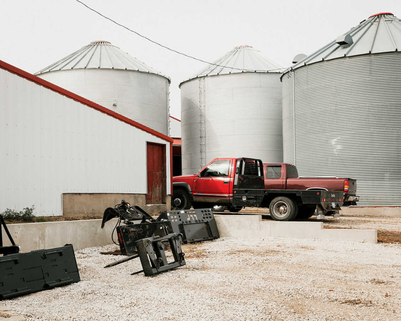 Attachments for a skid loader sit stacked near the silos at Huegerich's home base. After harvest, Huegerich has a busy winter planning for next year's crop.