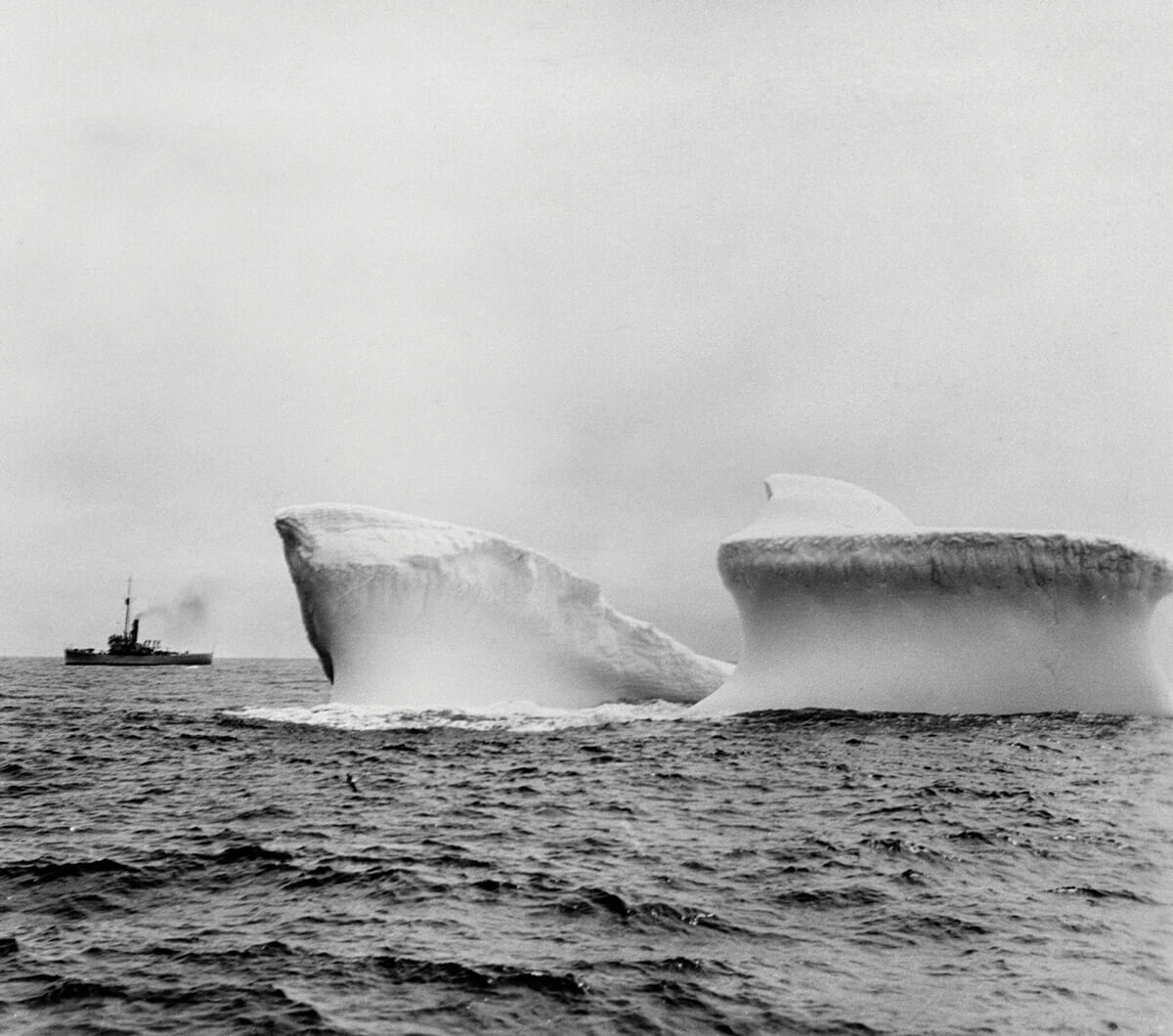 Ship sailing past iceberg in Antarctic waters.