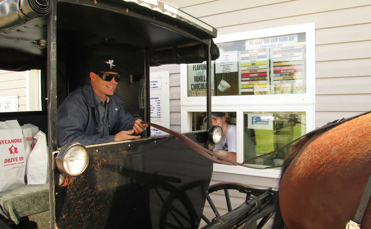 Vanilla Ice steering a horse and buggy through a drive through.