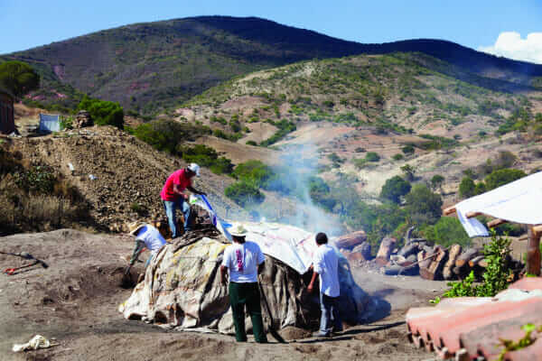 Workers cover the roasting pit.