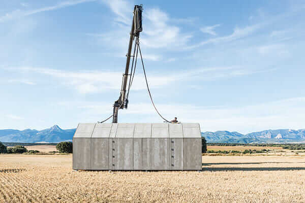 A crane deposits the Portable House in its new location.