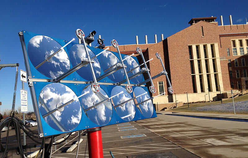 An array of parabolic mirrors focus light to be channels through bundles of fiber optic cables. 