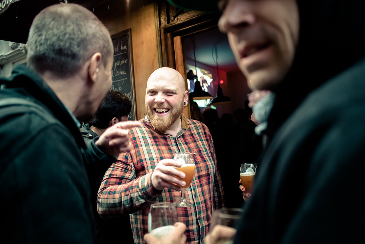 Co-owner of Les Trois 8, Julien Tisserand, shares a beer and a laugh with regulars on the first night of Paris Beer Week. / Courtesy Jean-Marie Heidinger