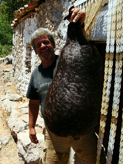 Cheesemaker Dimitris Hiotis holds a touloumi (the skin of a goat), which he will invert and then fill with cheese. The cheese will age in the skin for six months or more.
