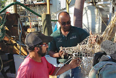 Thornell King repairs nets with one of his crew.