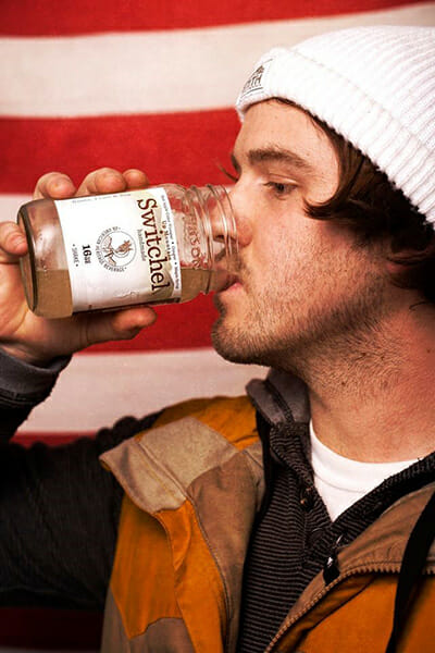A young man drinks a jar of handmade Up Mountain switchel.