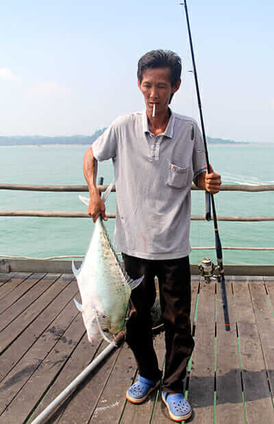 A fisherman poses with the catch of the day - a diamond trevally. Testament to declining fish populations, this was the first major catch of the weekend.