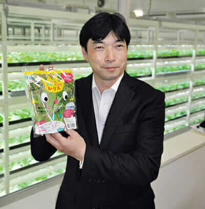 President Shigeharu Shimamura of Mirai Co. holds a bag of lettuce produced at a large-scale plant factory in Kashiwa. / Courtesy GE Lighting.