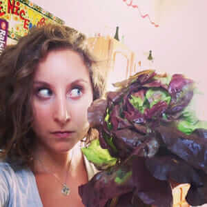 Schneider poses with lettuce that is the same size as her head.