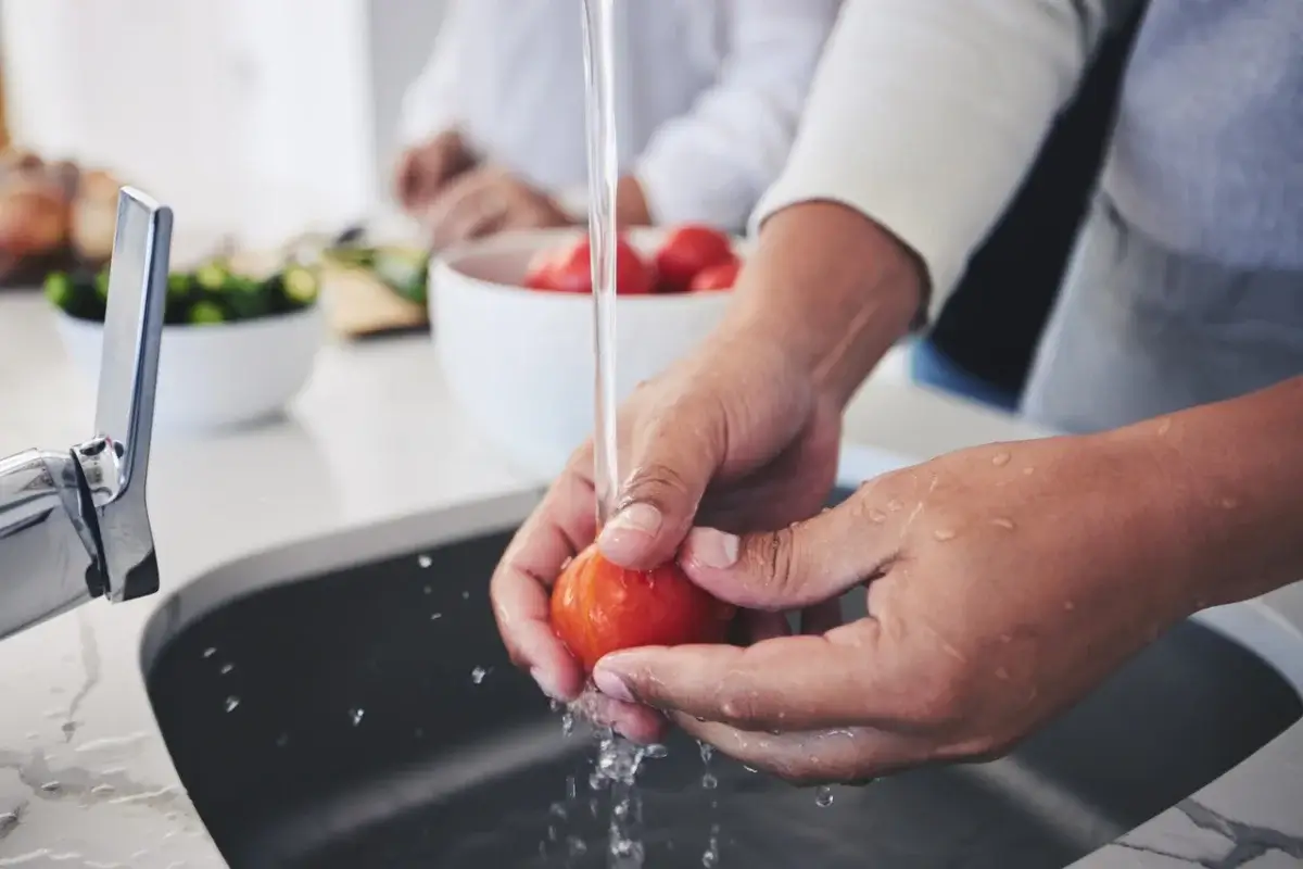 Hands washing a tomato