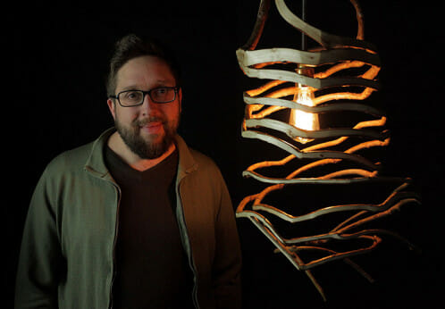 British furniture maker Gavin Munro stands with a lamp he grew. 