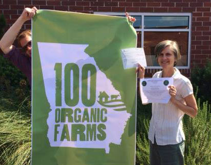 Alice Rolls displaying her Georgia Organic's first farm certification.