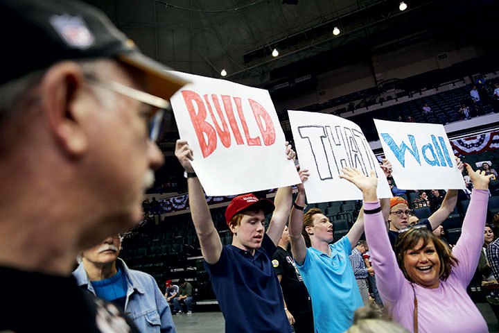 Trump supporters at a 2016 campaign rally in Tampa, FL, hold signs advocating strict border security.
