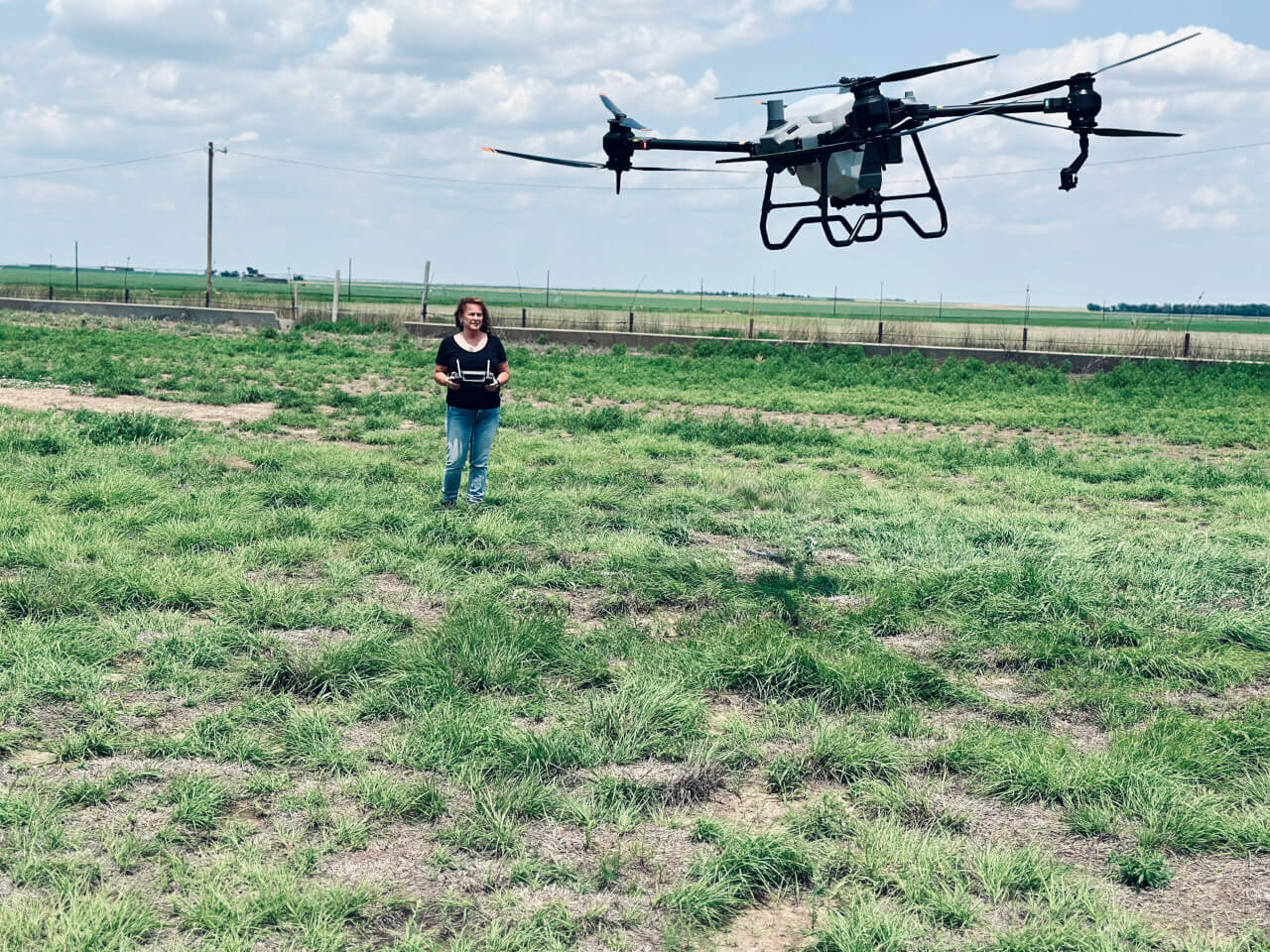 A person flies a drone in a field.