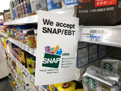 A sign in a grocery store that says "We accept SNAP/EBT."