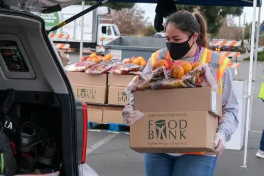 A person puts food donations into a car.