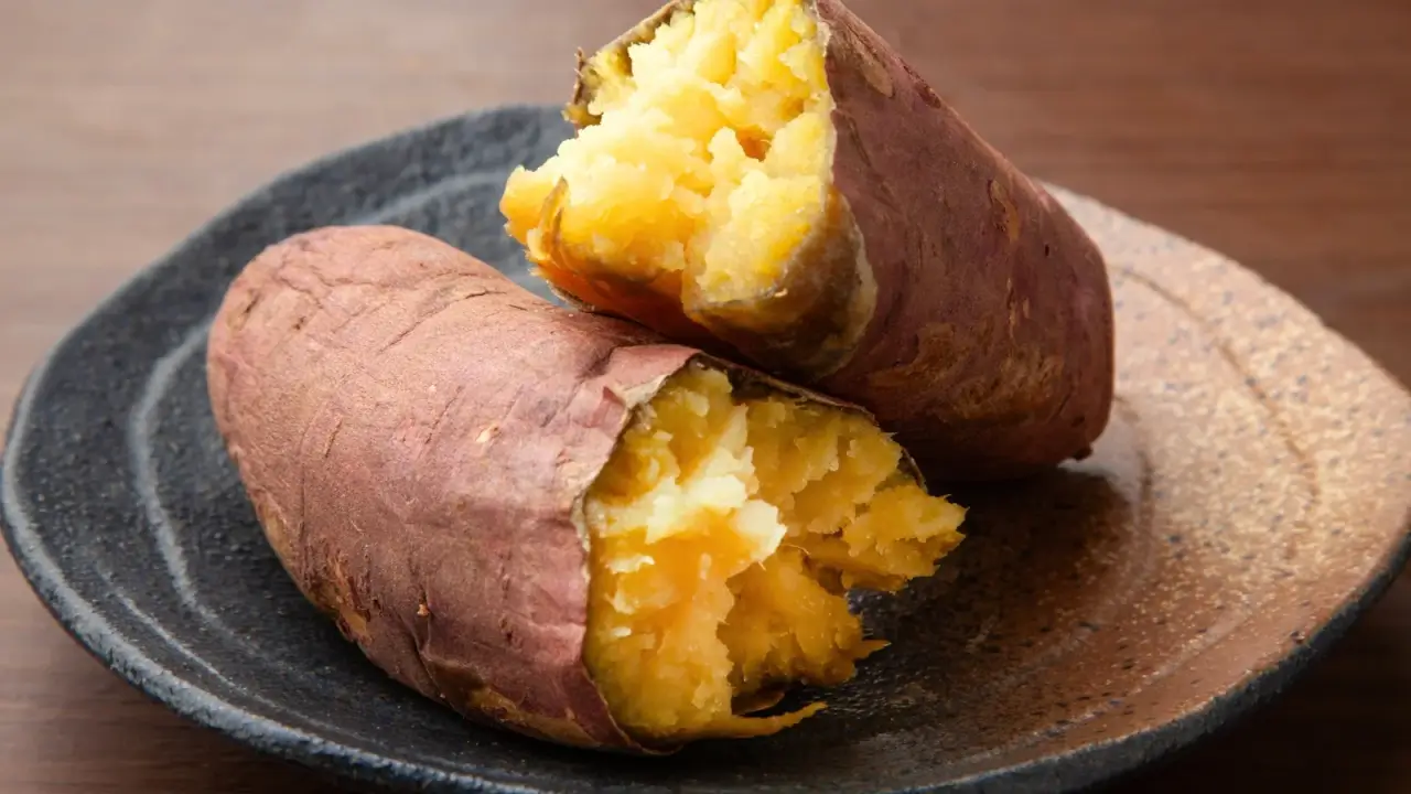 Two halves of a baked sweet potato with steaming, tender orange interior.